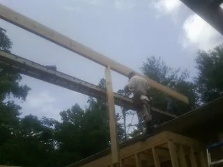 Carpenter setting a ridge beam over a new addition frame — Ice Dam Removal by Roofing Brothers in Poultney