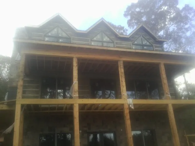 Dormers and porch framing on a large log home under construction — Roof Coating work by our crew in Poultney