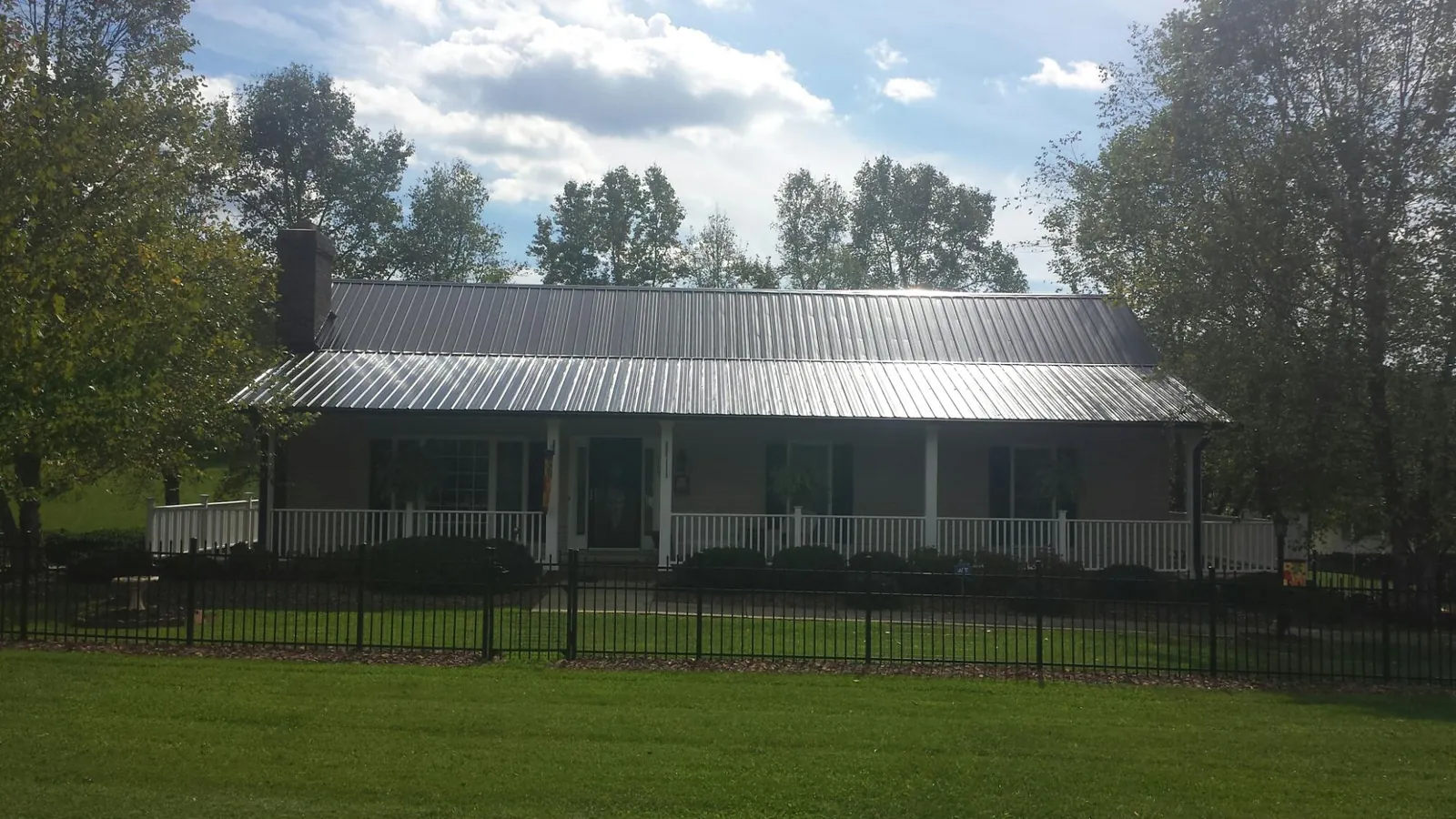 Gray metal roof on a brick ranch with a full width front porch — Gutter Guard Installation work by our crew in Poultney