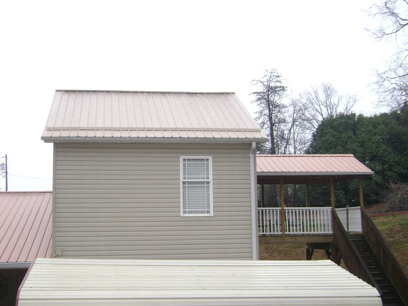 Tan metal roofs on a two story addition and attached porch, from a Roof Replacement job in Poultney